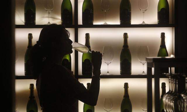 A woman poses with a glass of wine at a tapas bar in Mumbai