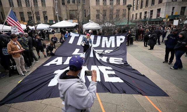 Eine Anhängerin zerrt an einem Trump-kritischen Plakat. Vor dem Gerichtsgebäude versammelten sich Demonstranten und etliche Journalisten.