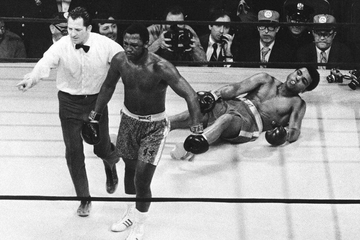 Erst 1970 kehrte Ali zurück in den Ring. 1971 trat er im Madison Square Garden dem ungeschlagenen Weltmeister Joe Frazier gegenüber. Das als "Kampf des Jahrhunderts" vermarktete Duell endete mit einem Punktsieg für Frazier. In der 15. und letzten Runde ging Ali zum ersten und einzigen Mal in seiner Karriere zu Boden (Bild).