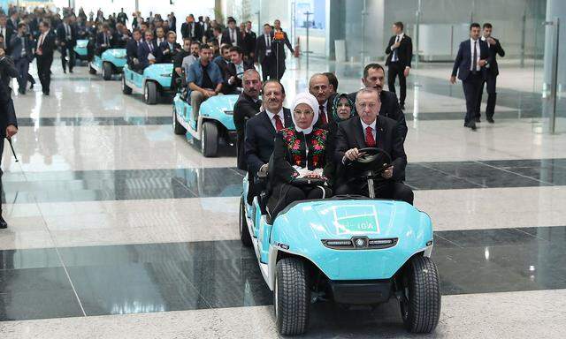 Turkey's President Tayyip Erdogan drives an airport golf cart with his wife Emine Erdogan and officials during the official opening ceremony of Istanbul's new airport in Istanbul