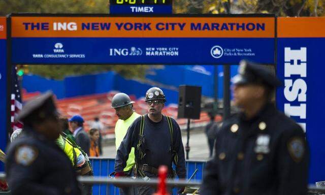 Workers install platform after the ceremonial painting of the New York City Marathon blue line at Central Park in New York