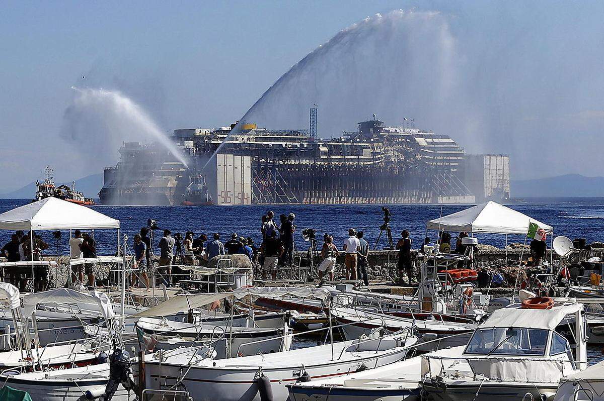 Mit Fontänen wurde das Auslaufen der Costa Concordia zu ihrer letzten Fahrt begleitet.