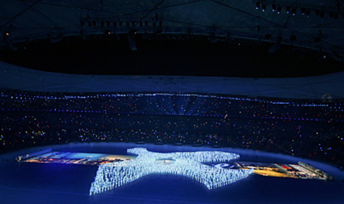 Hunderte in Blaulicht floureszierende Menschen formten eine Friedenstaube als Ausdruck der Hoffnung auf friedliche Spiele.
