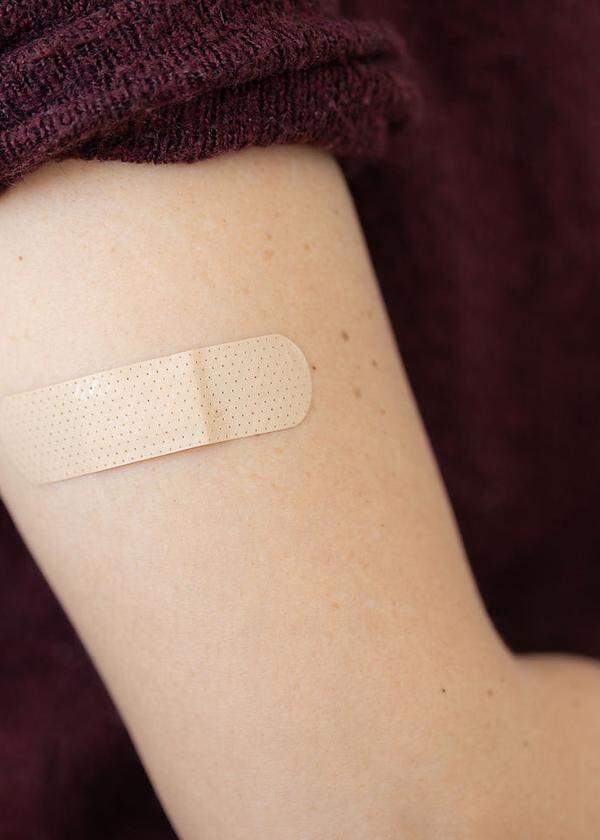 Adhesive bandage on arm of a female after taking vaccine