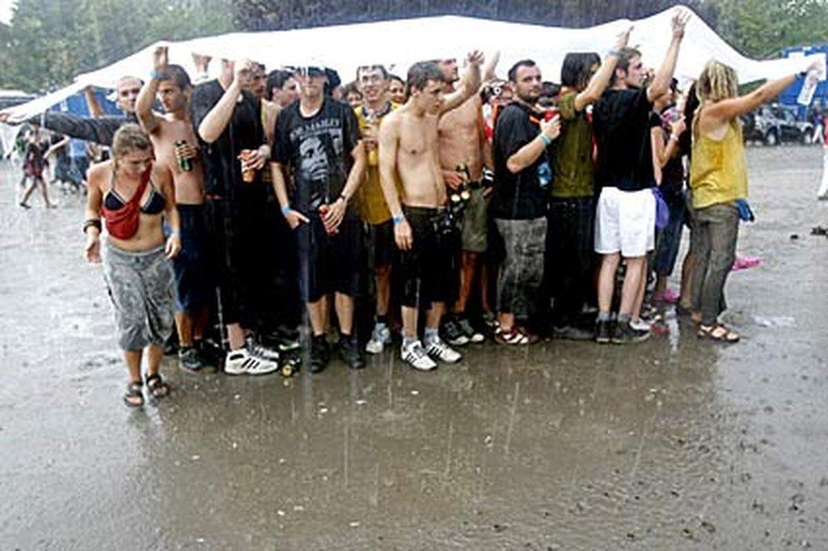 Körperkontakt garantiert: Damit sie nicht nass werden, haben sich diese Festivalbesucher einen Regenschutz gebastelt.