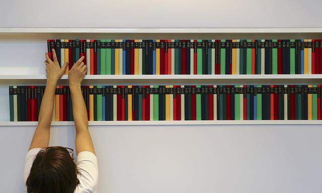 A woman sorts books at a Diogenes Verlag booth prior to the opening of the book fair in Frankfurt