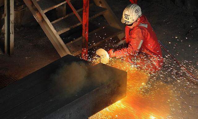 A steel worker cleans a block of steel at Voestalpine steel plant, which works in close co-operation with Austrian fireproof materials maker RHI, in Donawitz