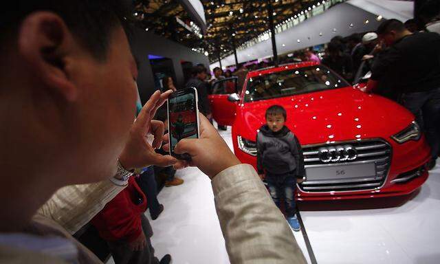 A man takes a picture of his son in front of an AUDI S6 car during the 15th Shanghai International Automobile Industry Exhibition in Shanghai