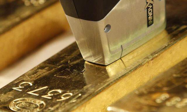 An employee of Deutsche Bundesbank uses metal analysis device on gold bar during a news conference in Frankfurt