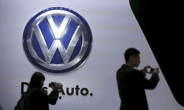File photo of visitors standing next to a Volkswagen logo in Shanghai