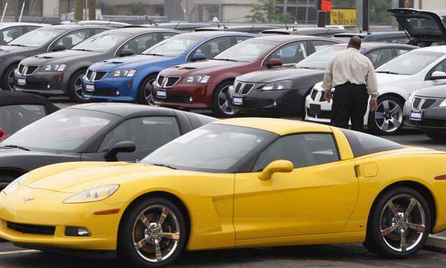 A car salesman walks through the parking lot at a General Motors 