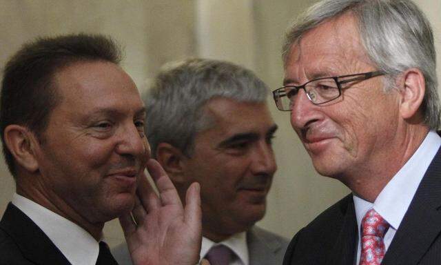 Luxembourg's PM Juncker pats Greek Finance Minister Stournaras on the cheek after a news conference in Athens