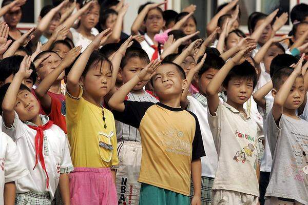 In China läuft der erste Schultag wenig überraschend sehr geordnet ab. Diese Erstklässler wohnen der Aufhängung der Chinesischen Flagge bei und salutieren stolz davor. Lehrpläne und 