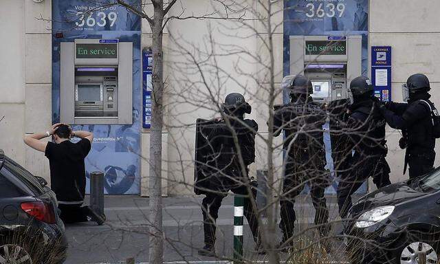 A suspect in a hostage taking situation is detained by members of special French RAID forces outside the post offices in Colombes outside Paris