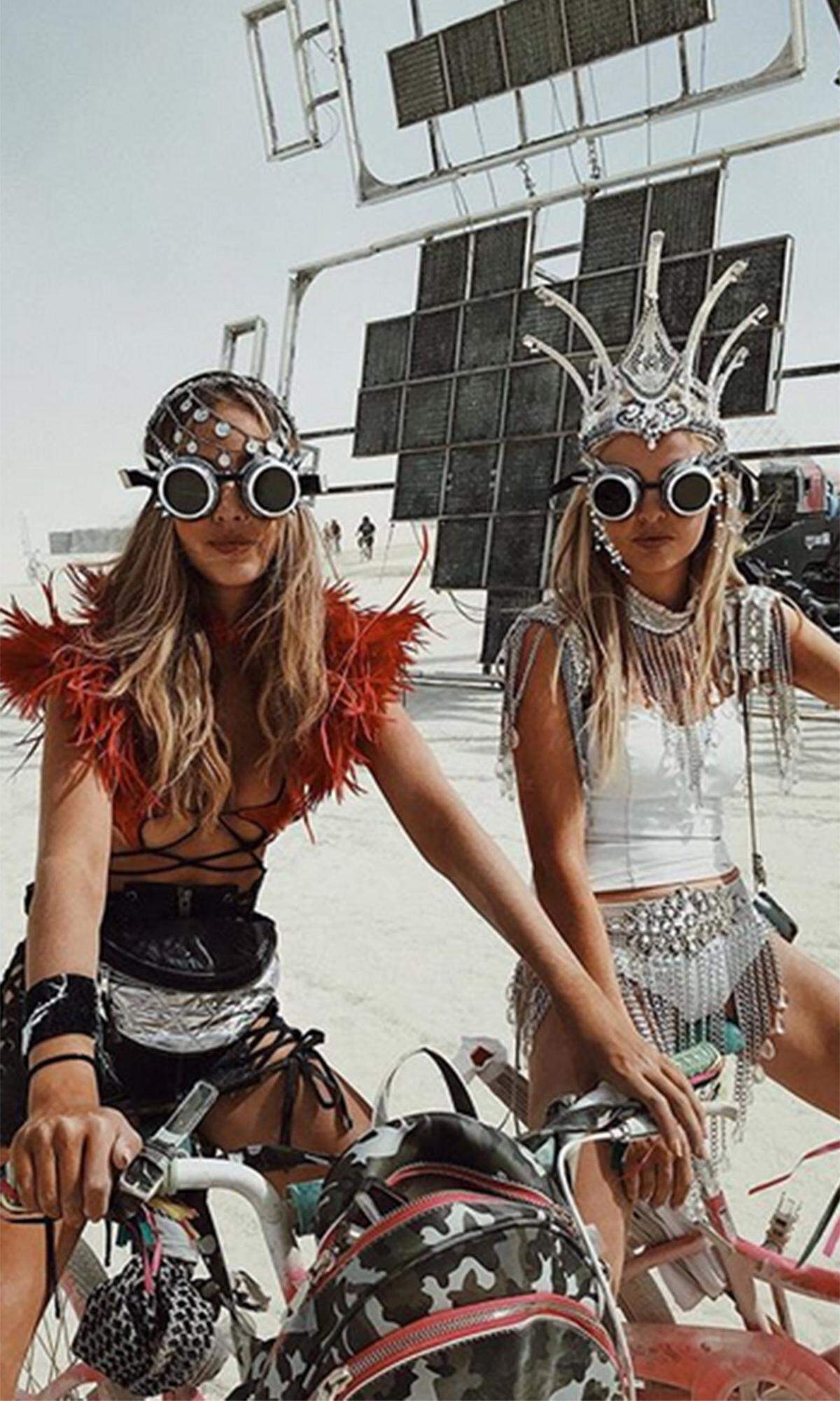 „Mad Max“ lässt grüßen: Zur „Burning Man“- Standardausrüstung gehören unbedingt eine Motorrad-, Taucher- oder Skibrille, um sich gegen den Wüstensand zu wappnen. Auch Model Rosa Crespo und ihre Freundin Lizzy Peridon wissen das -  und setzen den Look noch ein paar Federn, Nieten und eine Krone auf.