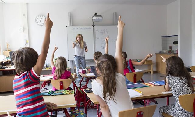 Active pupils raising their hands in class model released Symbolfoto property released PUBLICATIONx