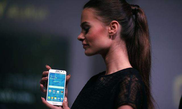 A model holds a Samsung Galaxy Alpha smartphone during a launch event in Jakarta