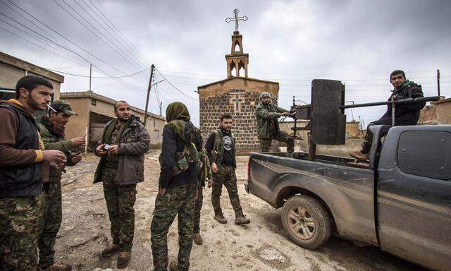 Fighters of the YPG stand near a pick-up truck mounted with an anti-aircraft weapon in front of a church in the Assyrian village of Tel Jumaa
