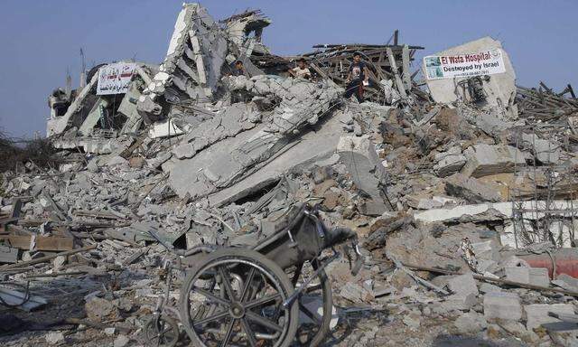 Wheelchair is seen as Palestinians stand atop the ruins of the headquarters of El-Wafa rehabilitation hospital, which witnesses said was destroyed during a seven-week Israeli offensive, in the east of Gaza City