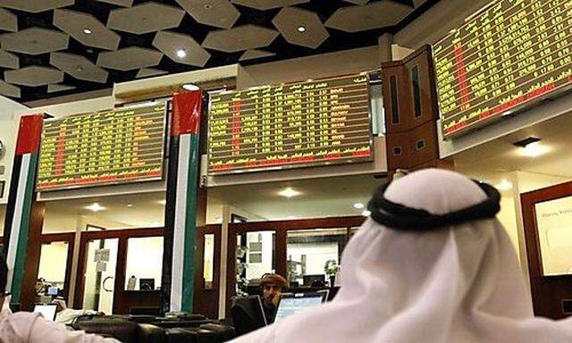 Investors look at stock exchange information at the Dubai Financial Market