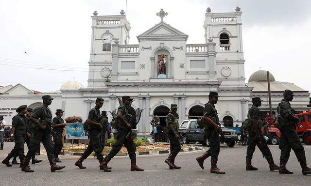 Soldiers and police officers walk past St. Anthony's Shrine in Colombo
