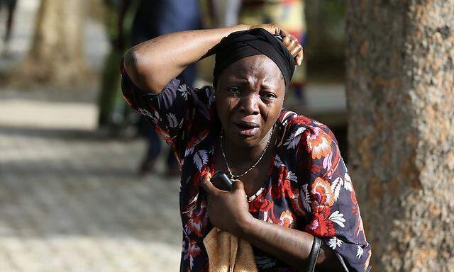 Bystanders react as victims of a bomb blast arrive at the Asokoro General Hospital in Abuja