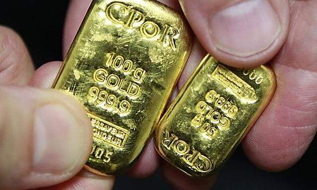 An employee displays 100 grams and 50 grams gold bars in an office of French gold supplier CPoR compa