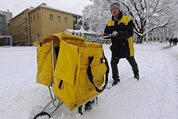 Ein Briefträger kämpft sich am Landestheaterplatz in Innsbruck durch den Schnee.
