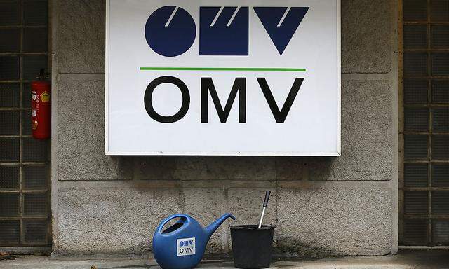 Watering cans are palced in front of the logo of Austrian energy group OMV at a gas station in Vienna