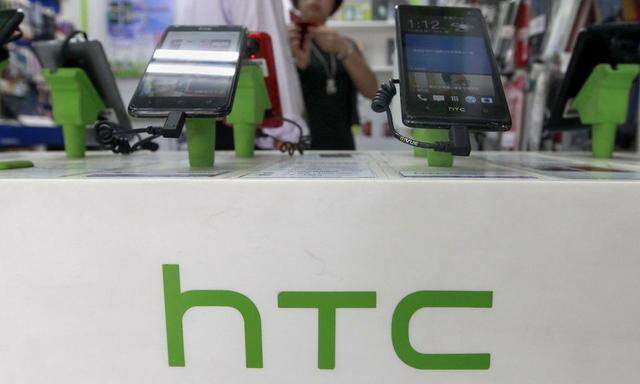 Customers look at HTC smartphones in a mobile phone shop in Taipei