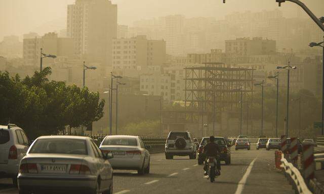 Motorists travel on a highway in Tehran as the city is covered in dust