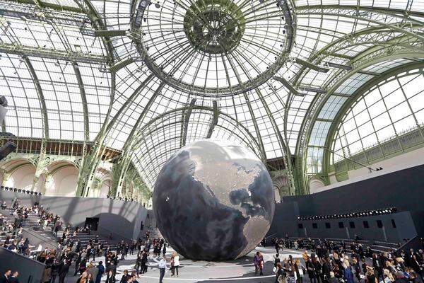 Das französische Modehaus platzierte eine gigantische Weltkugel in der Mitte des Laufstegs, verziert wurde die Szenerie von ausladenden Mänteln, Kostümen und Röcken in Schwarz und Nachtblau.