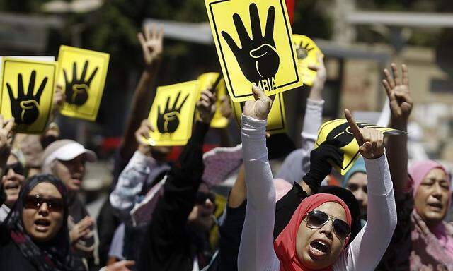 Members of the Muslim Brotherhood and supporters of ousted Egyptian President  Mursi make the 'Rabaa' gesture during a protest in Cairo