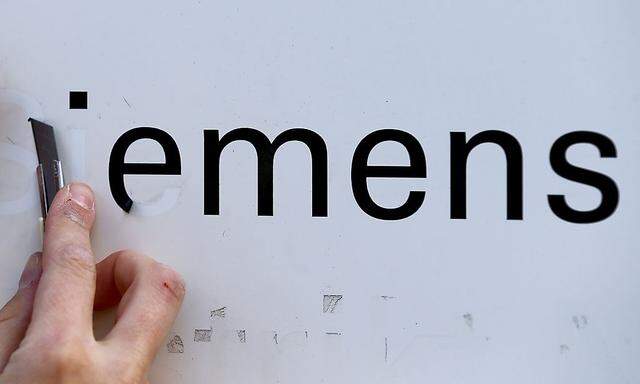 Worker removes Siemens lettering from information board at Siemens AG office building in Berlin