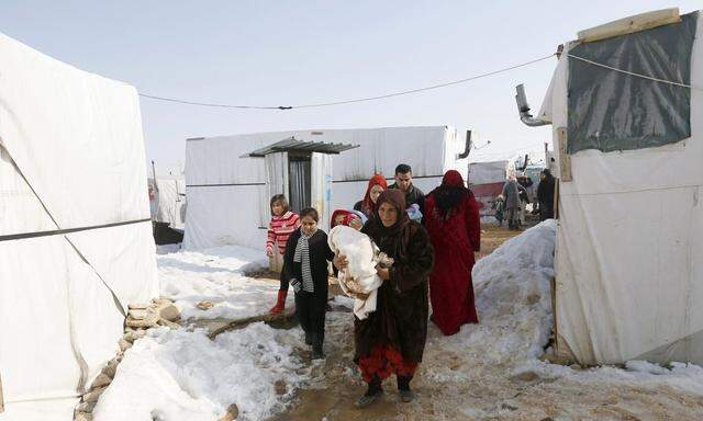 A Syrian refugee family carries 18-day-old triplets, whose mother died during childbirth in a nearby hospital, in a refugee camp near Zahle town in the Bekaa Valley