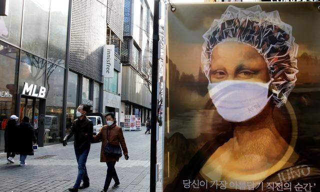 People wearing face masks walk past a poster depicting Mona Lisa with a protective face mask on a shopping street, amid the coronavirus disease (COVID-19) pandemic in Seoul