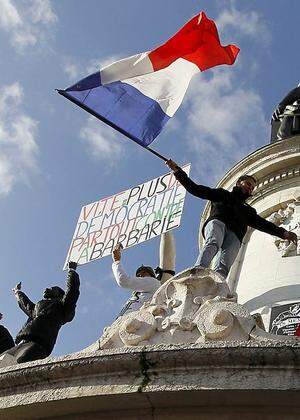 People holding a poster reading 'Quick more democracy everywhere against barbarism' take part in a solidarity march (Marche Republicaine) in the streets of Paris