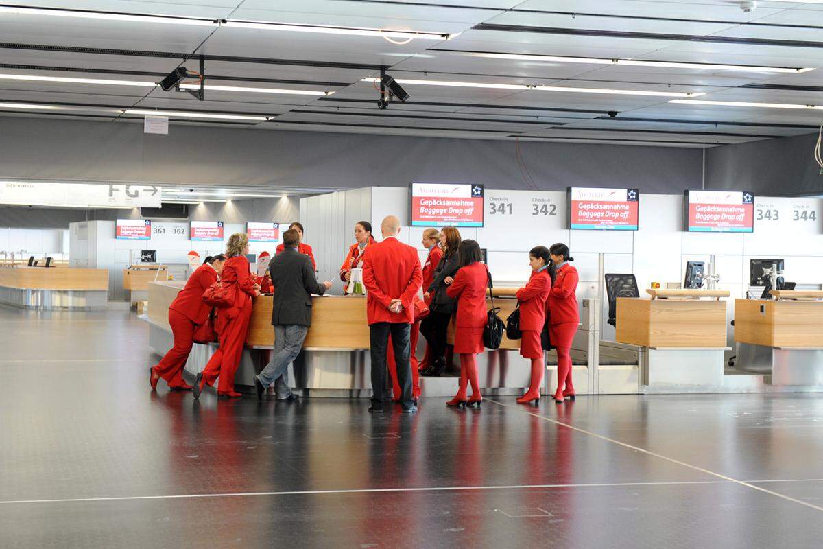 Und auch nicht die Menschen: Hinter den Check-in-Tresen steht AUA-Personal bereit – in roten Uniformen die kräftigsten Farbtupfer im grau-weißen Terminaldesign.