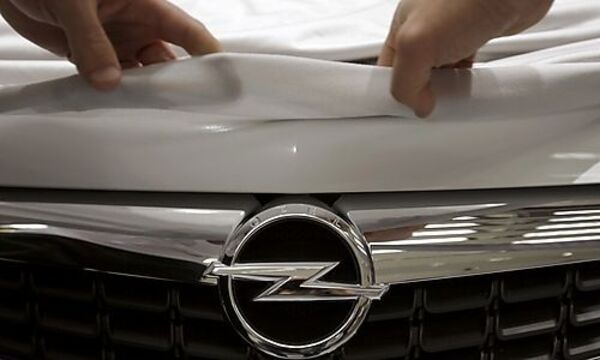 A worker for German car manufacturer Opel lifts the cover over the new company logo on a Astra car 