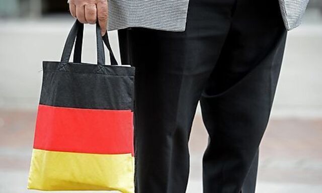 Man carries a shopping bag in the colours of the German national flag in downtown Hanove