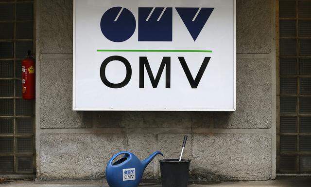 Watering cans are palced in front of the logo of Austrian energy group OMV at a gas station in Vienna