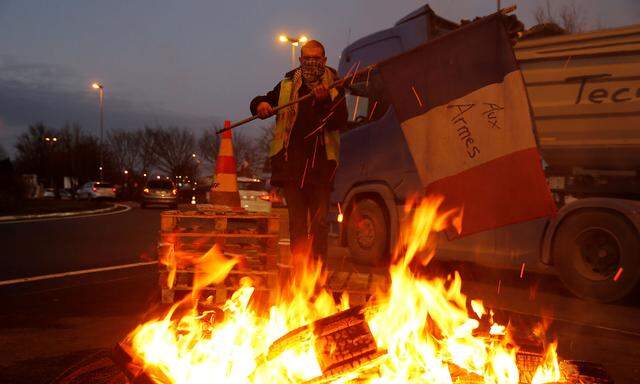 A protester wearing a yellow vest, the symbol of a French drivers' protest against higher fuel prices, holds a flag at the approach to the A2 Paris-Brussels Motorway, in Fontaine-Notre-Dame