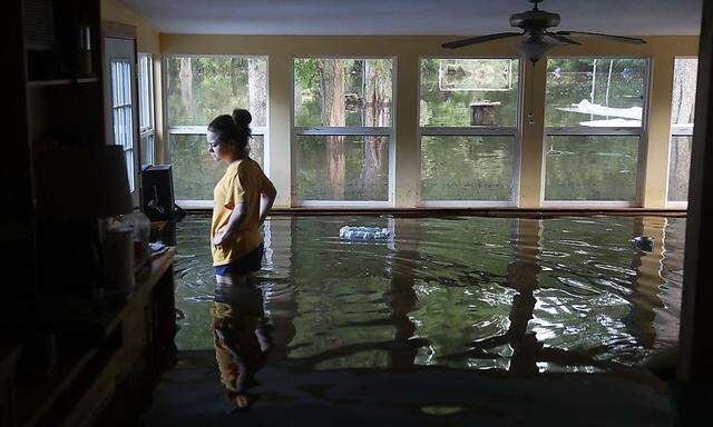 Eine Frau überprüft die Flutschäden in ihrem Haus.