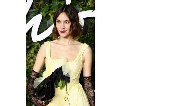 Model und Influencerin Alexa Chung grazil mit überlangen Spitzenhandschuhen und einem zartgelben Kleid von Caroline Hu.