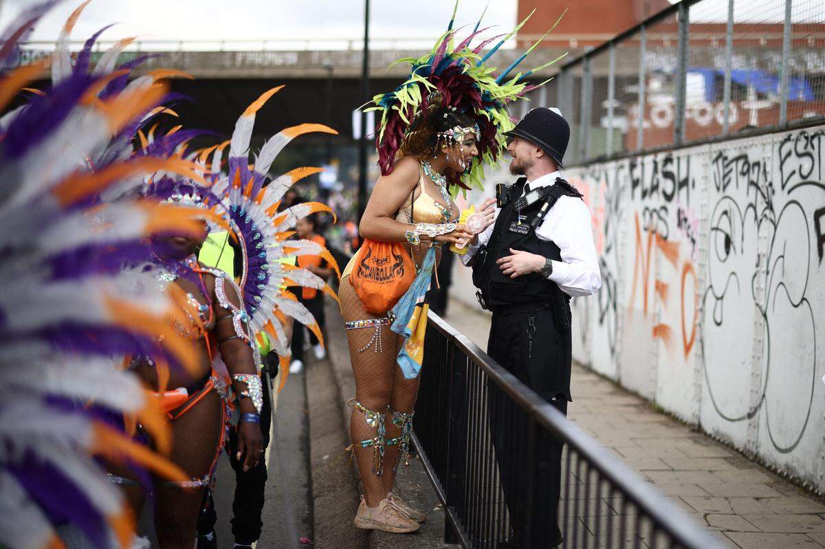 27. August. Ein Teilnehmer spricht während der Hauptparade des Notting Hill Carnival im Westen Londons mit einem Polizisten.