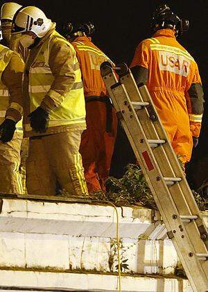 Rescue workers examine wreckage of a police helicopter which crashed onto the roof of a pub in Glasgow