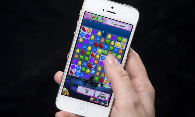 A woman poses in a file photo illustration with an iPhone as she plays Candy Crush in New York