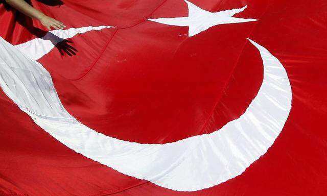 A protester touches a giant Turkish flag during a demonstration against outlawed Kurdistan Workers Party (PKK) in Istanbul