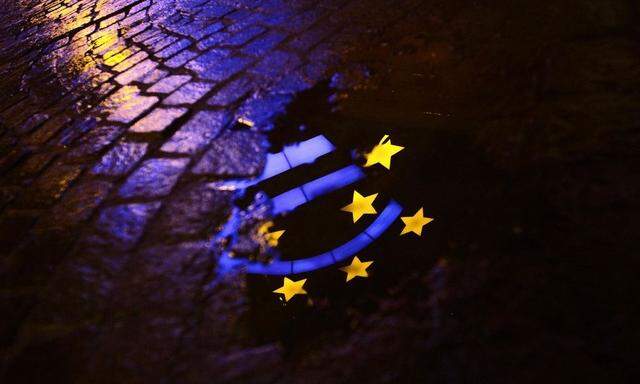 Euro sculpture is partially reflected in a puddle in front of the headquarters of the ECB headquarters in Frankfurt