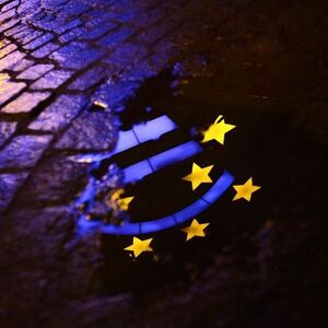 Euro sculpture is partially reflected in a puddle in front of the headquarters of the ECB headquarters in Frankfurt